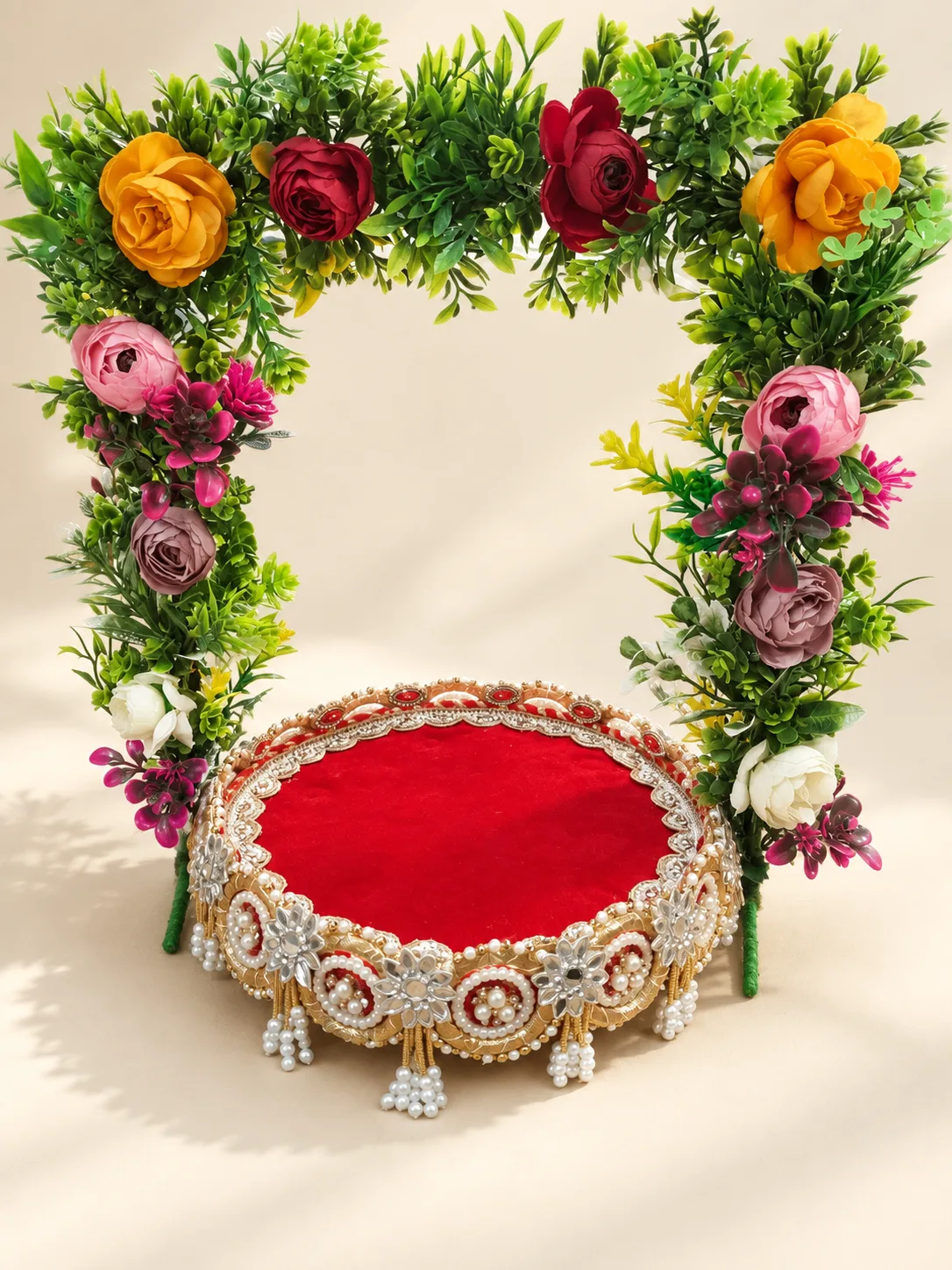 Floral arch above a red velvet aasan with pearl and silver trim